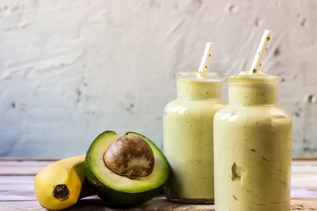 A close-up of a creamy green smoothie made with avocado and banana in glass jars, perfect for women's nutritional health.