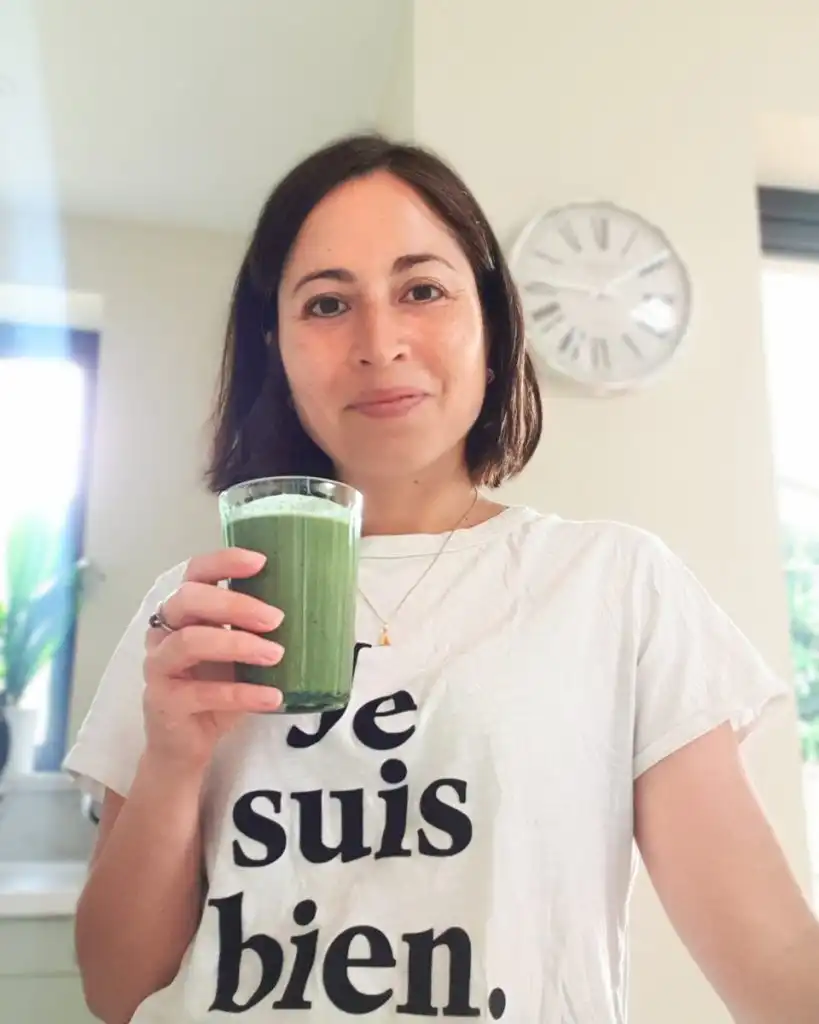 Woman holding green smoothie, promoting women's nutrition and wellness.