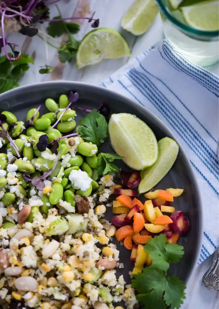 Colorful vegetarian salad with lime wedges and fresh herbs for women.